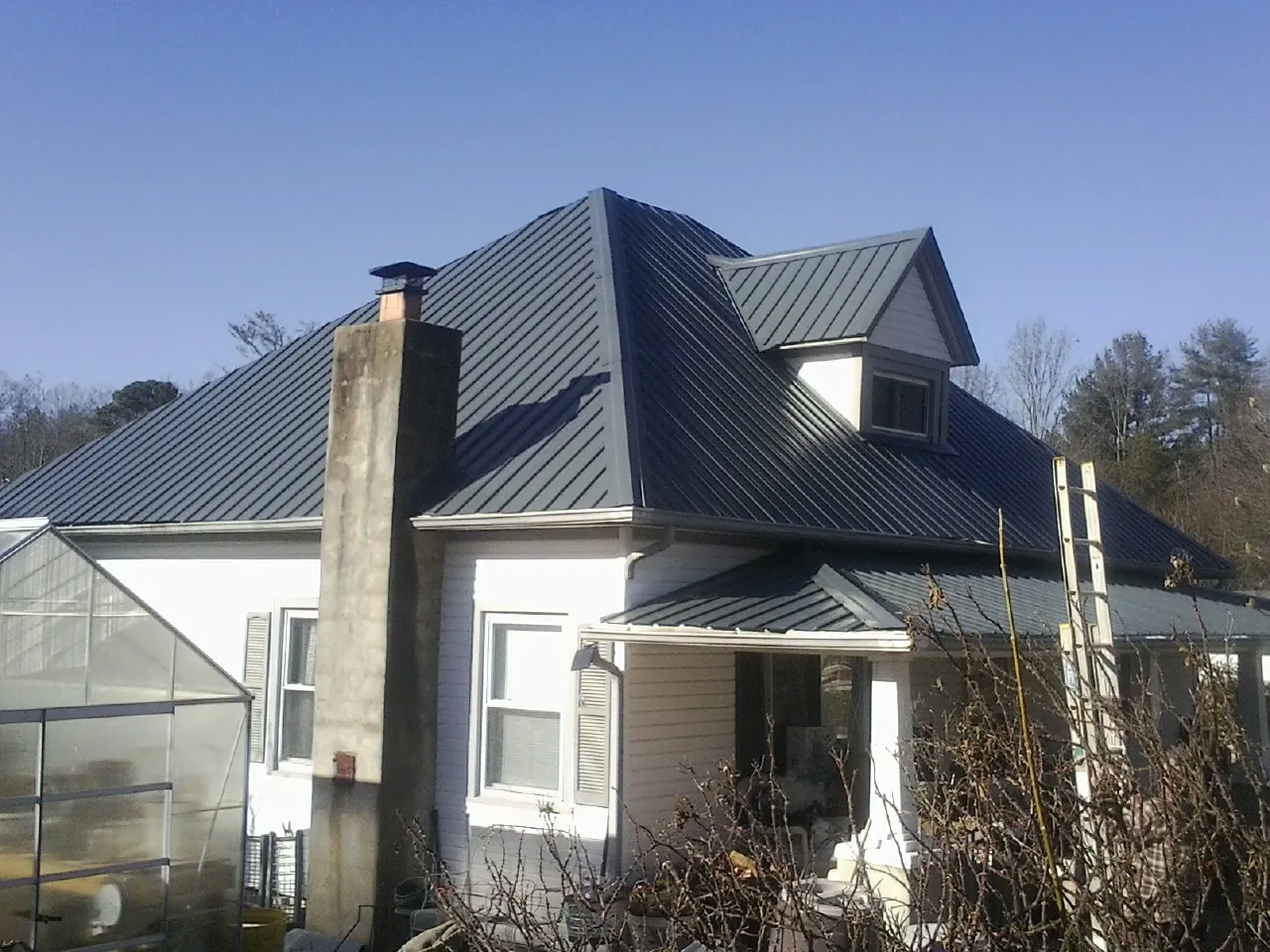 Dark blue standing seam metal roof on a white farmhouse with dormer — Slate & Tile Roof Repair by Roofing Brothers in Monteview