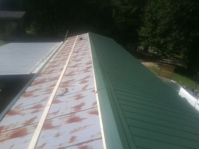 Old rusted panels beside newly installed green metal roofing — Wind Damage Roof Repair by Roofing Brothers in Monteview