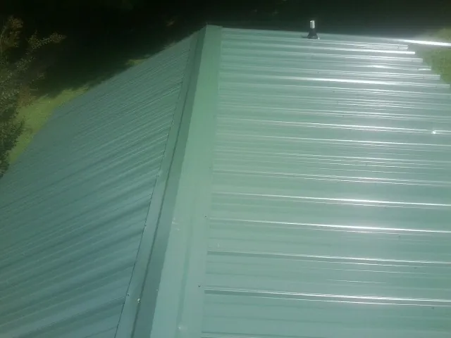 New green metal panels meeting at the ridge of a roof — Flat Roof Repair work by our crew in Monteview