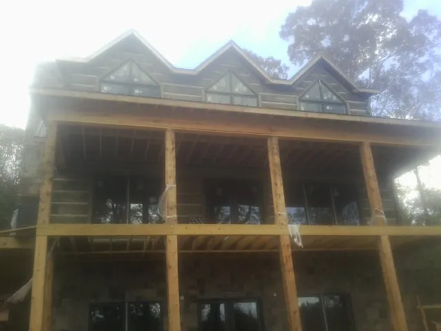 Dormers and porch framing on a large log home under construction — Roof Coating work by our crew in Monteview