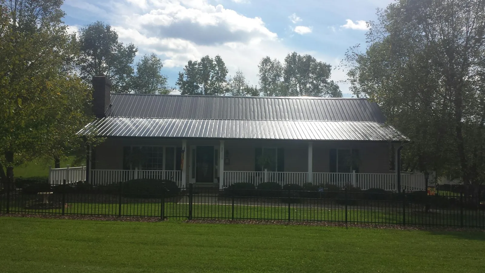 Gray metal roof on a brick ranch with a full width front porch — Gutter Guard Installation work by our crew in Monteview